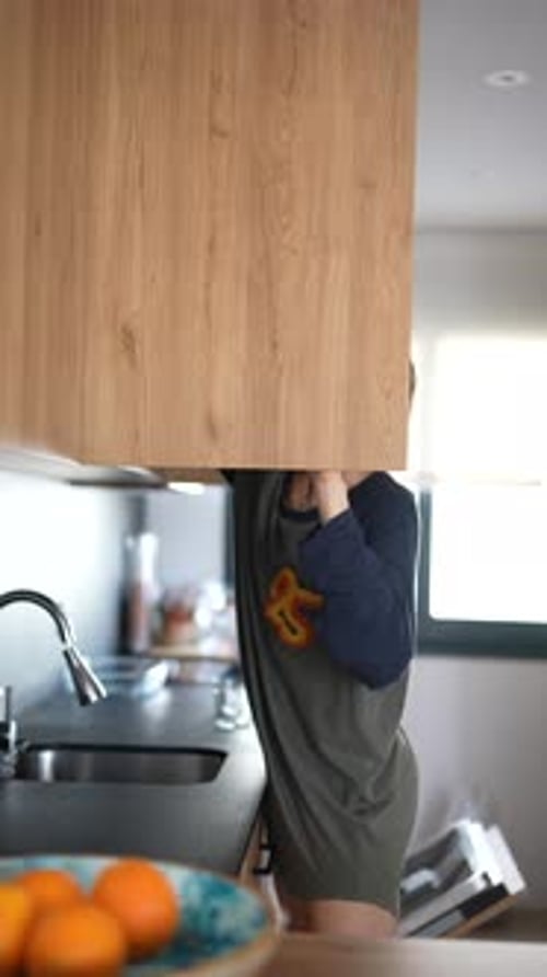 Woman Organizing Kitchen Cabinets in a Modern Home As Part of Daily Tasks in Contemporary Lifestyle
