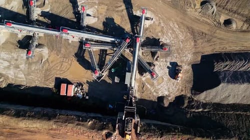 Video drone footage of a quarry showing machinery and mechanical extraction of gravel from it.
