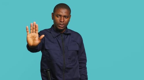 Man Giving Stop Hand Gesture on Blue Background