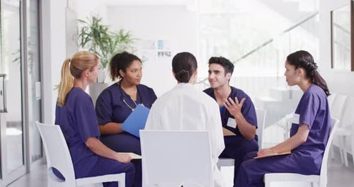 Video of diverse group of male and female doctors sitting in discussion in hospital meeting