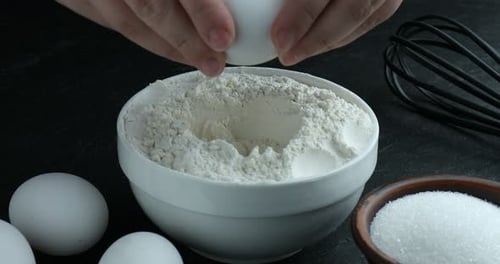 Baking preparation. Egg cracking in to flour bowl