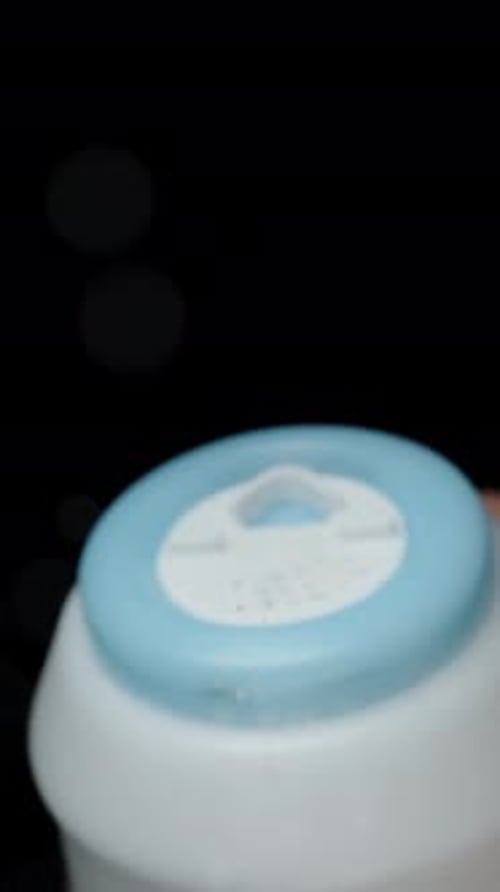 Vertical video. The chef salts the dish from a plastic salt shaker, and tiny salt particles slowly.