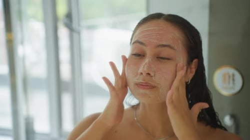 Hotel Bathroom Guest Gently Exfoliating Face at Mirror with Fine Scrub Slow Circular Massage Window