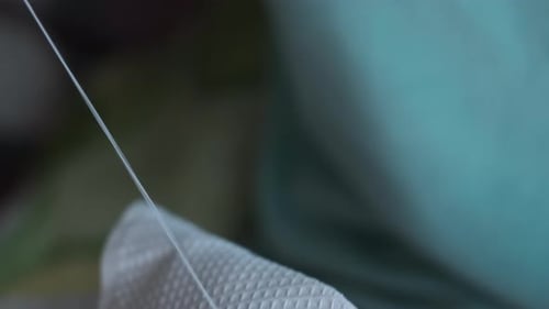 Woman's Hands Skillfully Sewing White Material