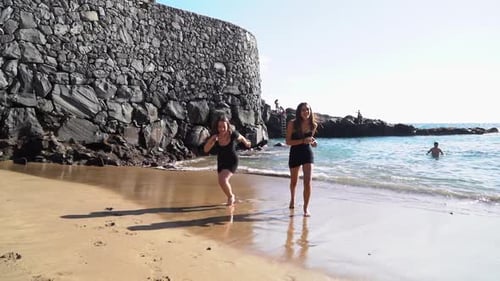 Two Women Running on the Beach Shore