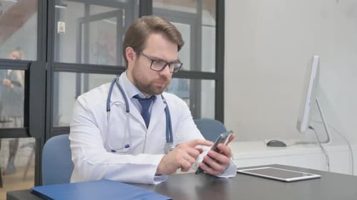 Mature Adult Doctor Working on Smartphone in Hospital