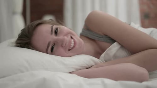 Close Up of Young Woman Smiling at Camera in Bed