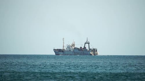 Fishing Boat Trawler Catches Fish While Sailing on Sea A Commercial Fishing Boat on the Horizon in a
