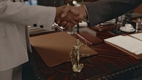 Making Legal Agreement with Handshake over Themis Statue in Hall
