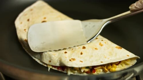 Quesadilla Cooking in Pan with Spatula Pressing