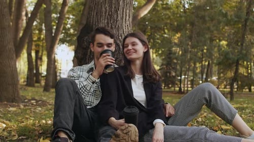 Schönes junges Paar, das ein angenehmes Gespräch führt und heiße Getränke aus Einwegbechern trinkt