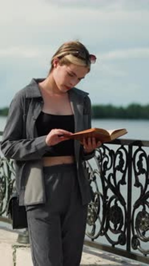 Young Woman Reads Book by Decorative Railing