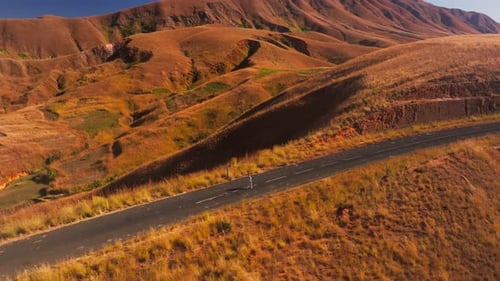 Caucasian Girl Walks Along a Winding Road in the Highlands of Madagascar The Landscape is Arid and