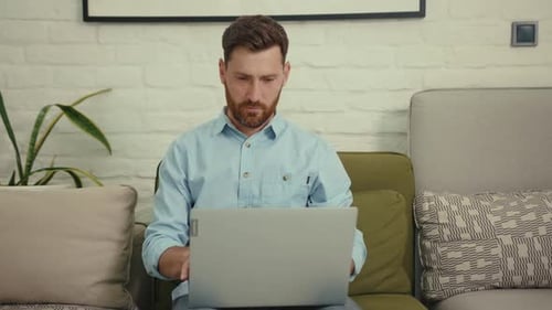 Man working on laptop at home on sofa