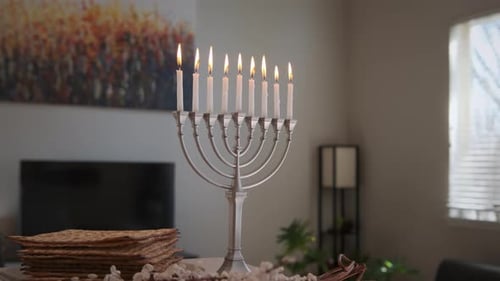 Velas de colores encendidas para Janucá en la menorá de Hanukkah y los rayos del sol sobre un fondo borroso en casa