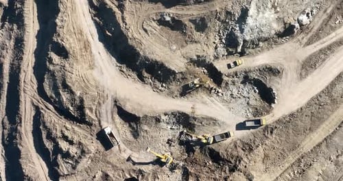 Industrial Mine Excavators are Digging the Soil in the Construction Site and Loading Trucks