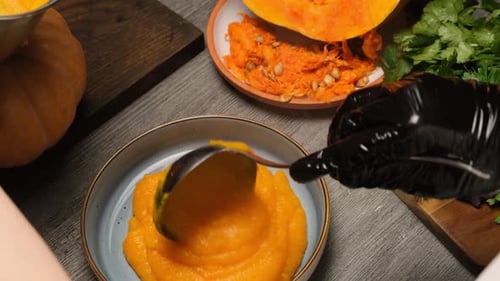Glättender heißer Kürbisbrei aus Edelstahl in einer Schüssel mit kreisförmigen Bewegungen Vegetarisches Essen von