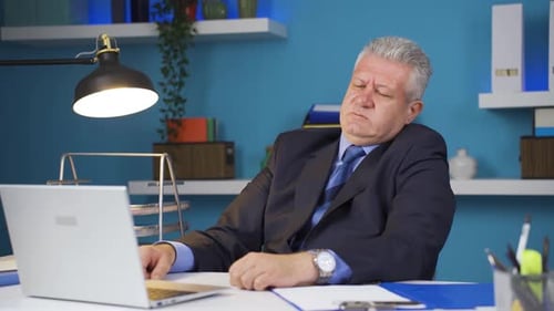 Tired Businessman Working on Laptop in Office