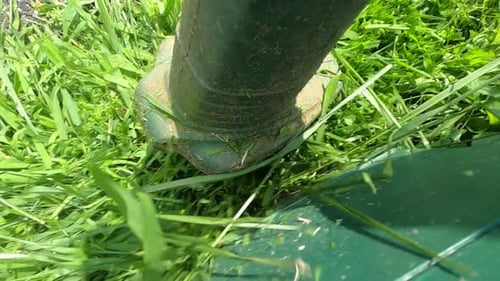 Zeitlupenaufnahmen eines Unkrautschneiders, der Gras räumt.