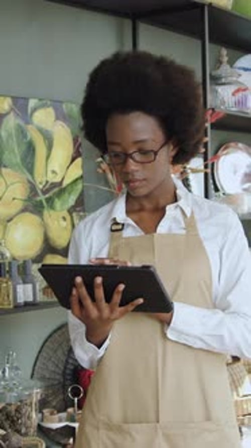Young Woman Uses Tablet in Shop, Smiling