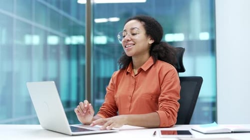 Happy african american businesswoman finished work on laptop while sitting at workplace in office.