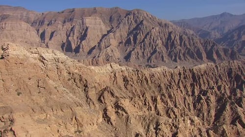 aerial view of ancient mountain range in the middle of the desert peaking in blue sky