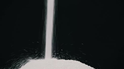 Sugar Pours in a Stream on a Black Background in Slow Motion CloseUp