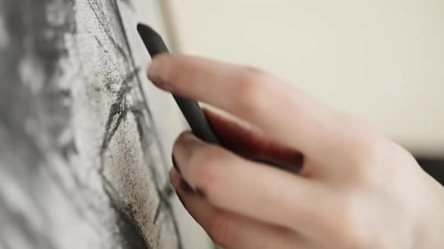 Closeup of an Artist's Hand Sketching and Blending Charcoal on Textured Paper Shaping Expressive