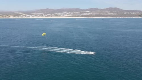 Aerial: tourists parasailing off coast on summer vacation