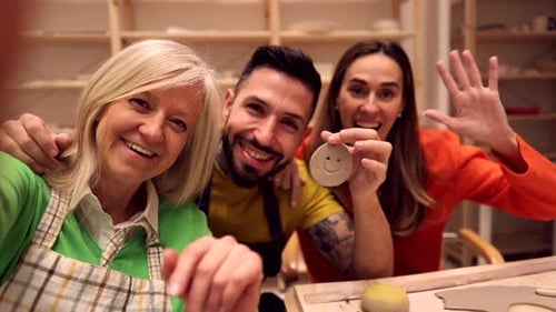 Joyeux participants à l'atelier de poterie saluant la caméra