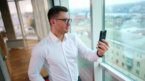 Young Adult Using Cell Phone By Window