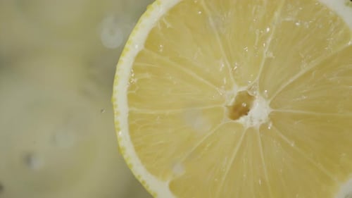 Flüssigkeitstropfen, die in Zeitlupe auf frisch geschnittene Zitronenstücke fallen, wunderschönes Eiswasser spritzen darauf