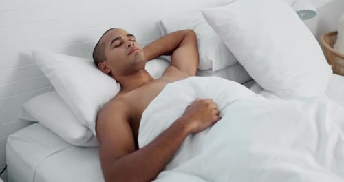 Young Man Relaxing in Bed with White Sheets