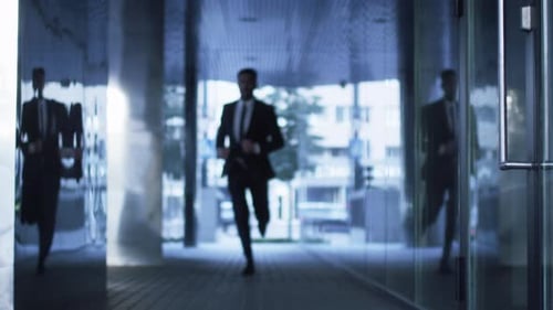 Businessman Running on Streets of Business District. Slow Motion Shot.