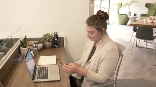 Mid Adult Businesswoman Using Smartphone In Modern Office