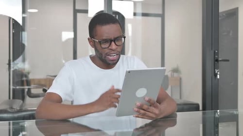 Young African Man Doing Video Chat on Tablet in Office
