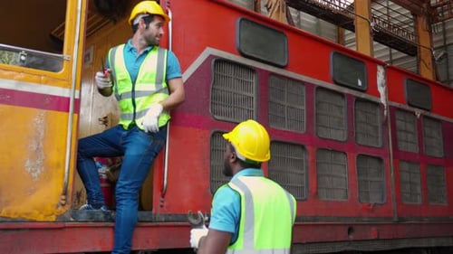Young caucasian and black engineer maintenance and repair train diesel engine in station.