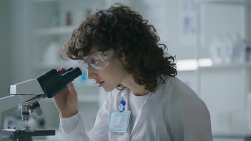 Woman Scientist Using Microscope in Bright Laboratory
