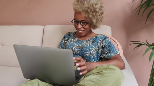 Woman Smiles Working on Laptop at Home