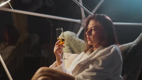 Woman Relaxing in White Robe with Champagne Indoors