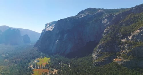 Sunlit wooded valley among the mountains of Yosemite National Park, California, USA.