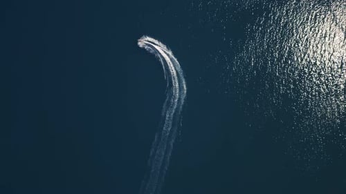 Aerial View of a Jet Ski Speeding Across Dark Blue Water Leaving a Dynamic White Trail Captured By