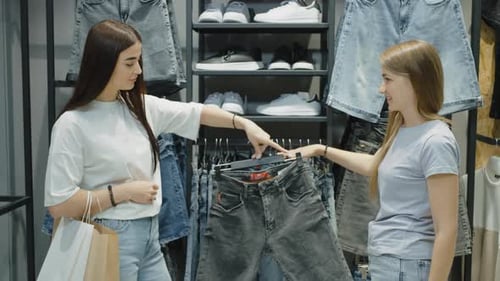 Happy women choosing jeans shorts at clothes store