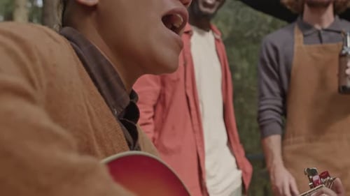Man Playing Guitar with Friends Outdoors