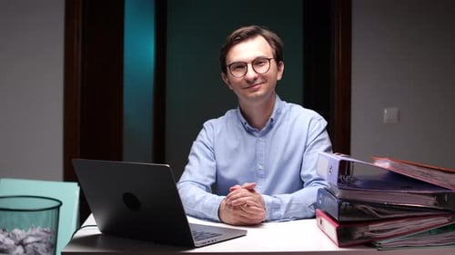 Office Worker Smiling at Desk with Laptop and Files