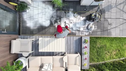 Man Cleaning His Backyard Garden Patio Using High Pressure Washer