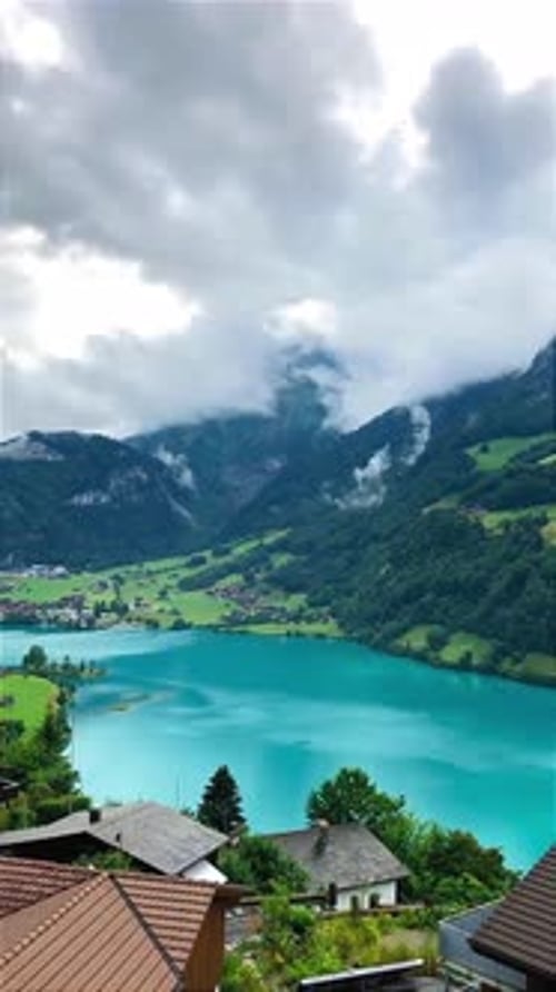 Scenic Alpine Lake with Mountain View and Village Below Clouds