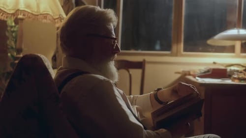 Senior Man Reading Book in Cozy Home at Night