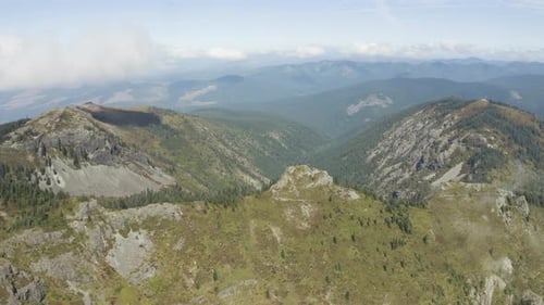 Drone en orbite et s'élève au-dessus de montagnes ouvertes et d'un ciel parsemé de nuages vaporeux, Silver Star Mountain Washin