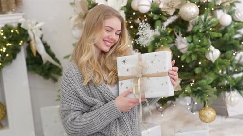 Woman Holding Christmas Gift in Decorated Room